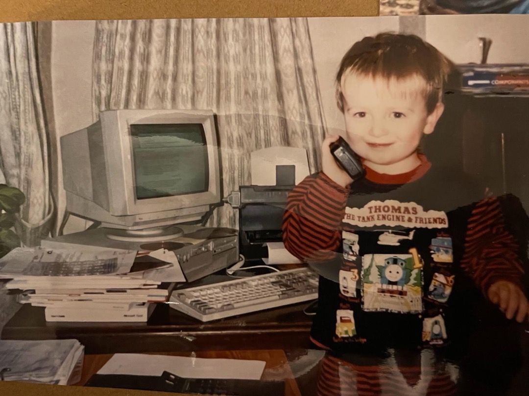 Tom as a small boy on the phone in a Thomas the Tank Engine top